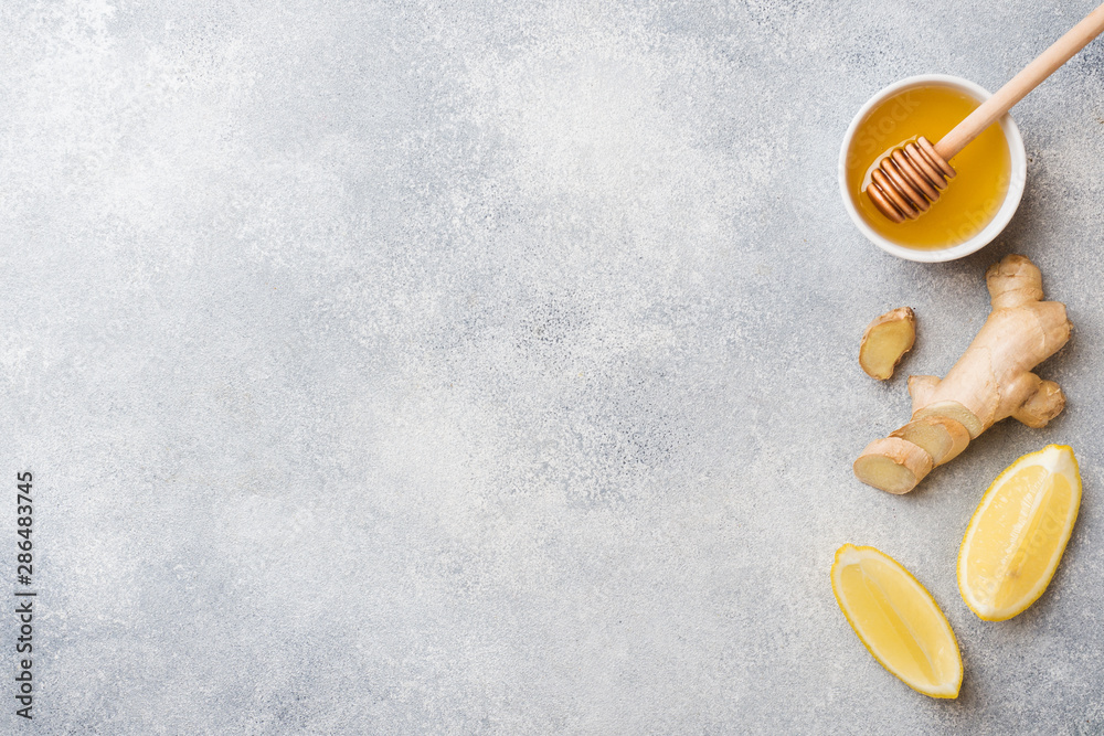 Lemon honey and ginger root on grey background with copy space. Ingredients for a tonic vitamin drink. Lemon honey and ginger root on grey background with copy space. Ingredients for a tonic vitamin drink.