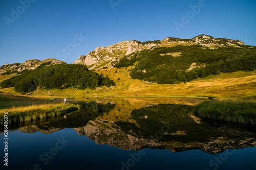 Photographer taking photo on mountain lake in summer.  photo