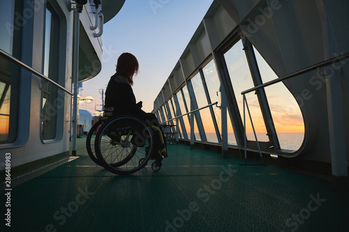 Young woman in wheelchair in sunset on a cruise ship