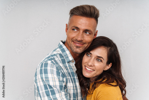 Cheerful happy adult loving couple isolated over grey wall background.