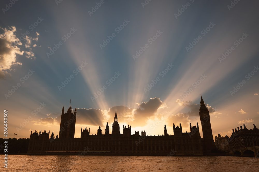Fototapeta premium Dramatic sun beams behind the Palace of Westminster as the sun sets in London.