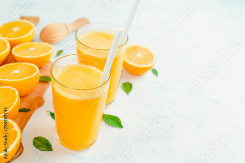 Orange juice and orange fruits with green leaves on white background.