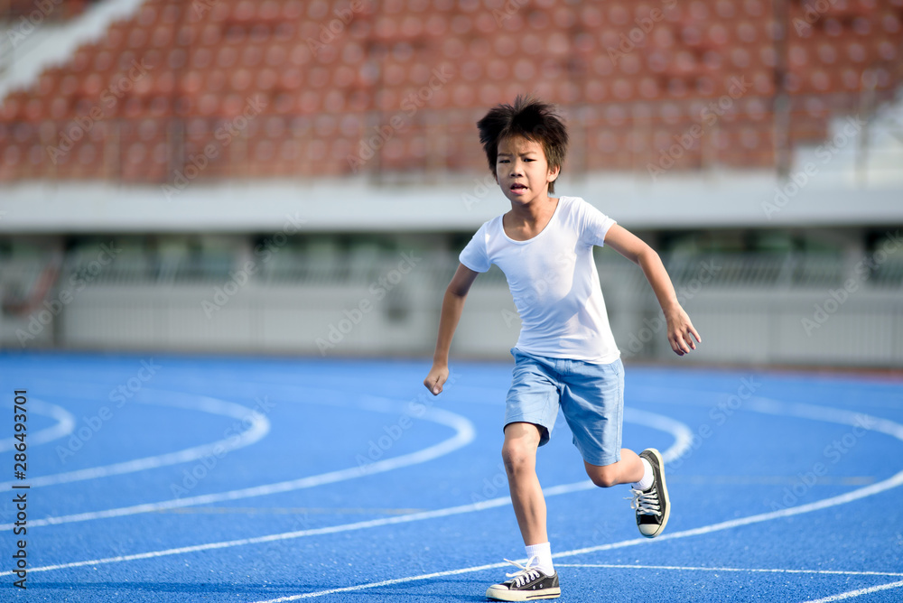 Obraz premium Young boy running on blue track