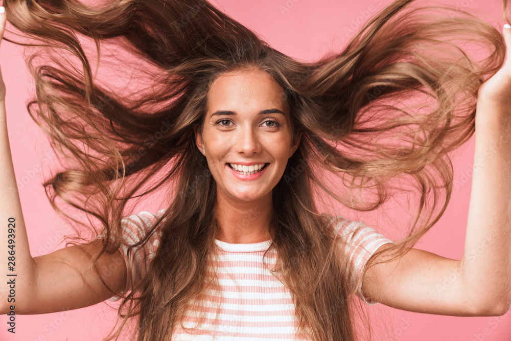 Image closeup of young beautiful woman dressed in casual clothes smiling and having fun with flying hair Image closeup of young beautiful woman dressed in casual clothes smiling and having fun with flying hair