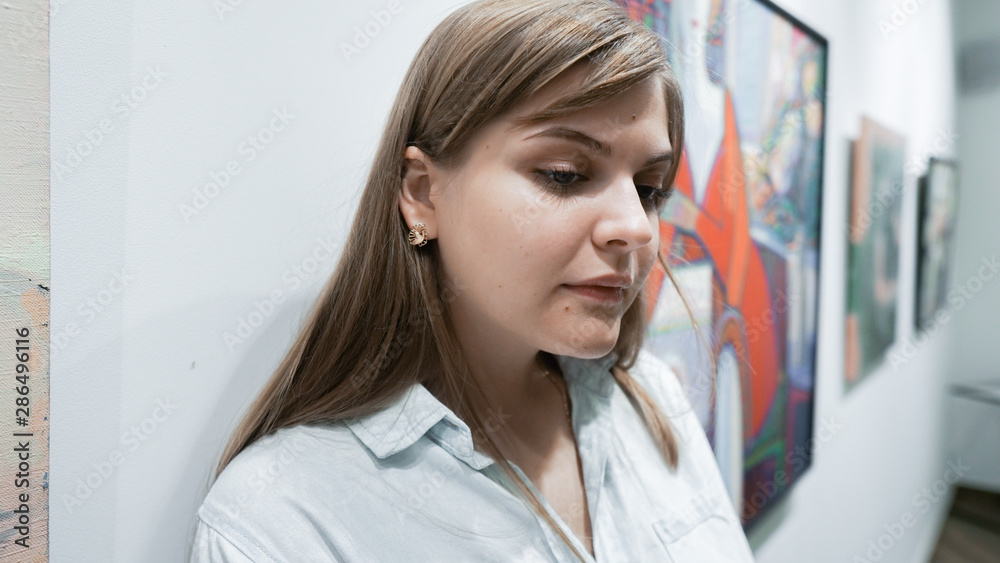 Young Woman Visiting Art Gallery Lifestyle Concept. Girl looking at modern painting in art gallery Young Woman Visiting Art Gallery Lifestyle Concept. Girl looking at modern painting in art gallery