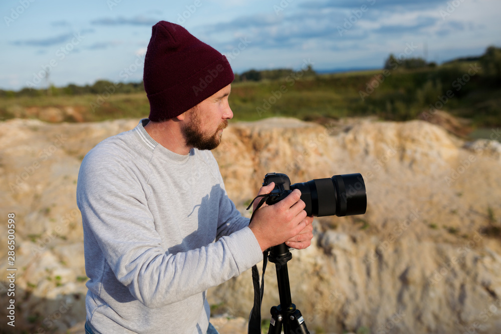 Bearded hipster photographer with a camera in his hands shoots wildlife Bearded hipster photographer with a camera in his hands shoots wildlife