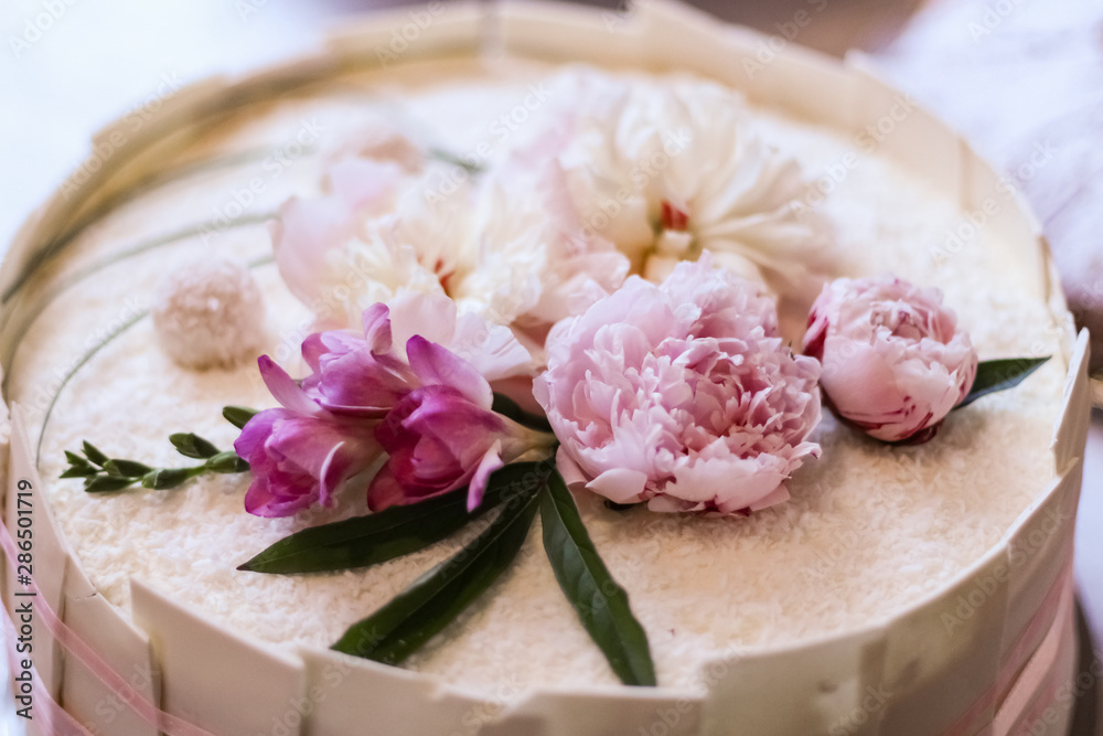 A beautiful custom made wedding cake with white chocolate walls and a bow. Coconut sprinkles and pink Peony flowers on top. A beautiful custom made wedding cake with white chocolate walls and a bow. Coconut sprinkles and pink Peony flowers on top.