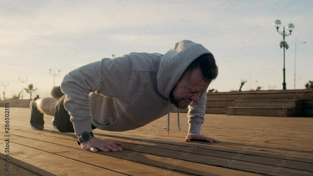 Exhausted man is doing push-ups and falling on ground without force