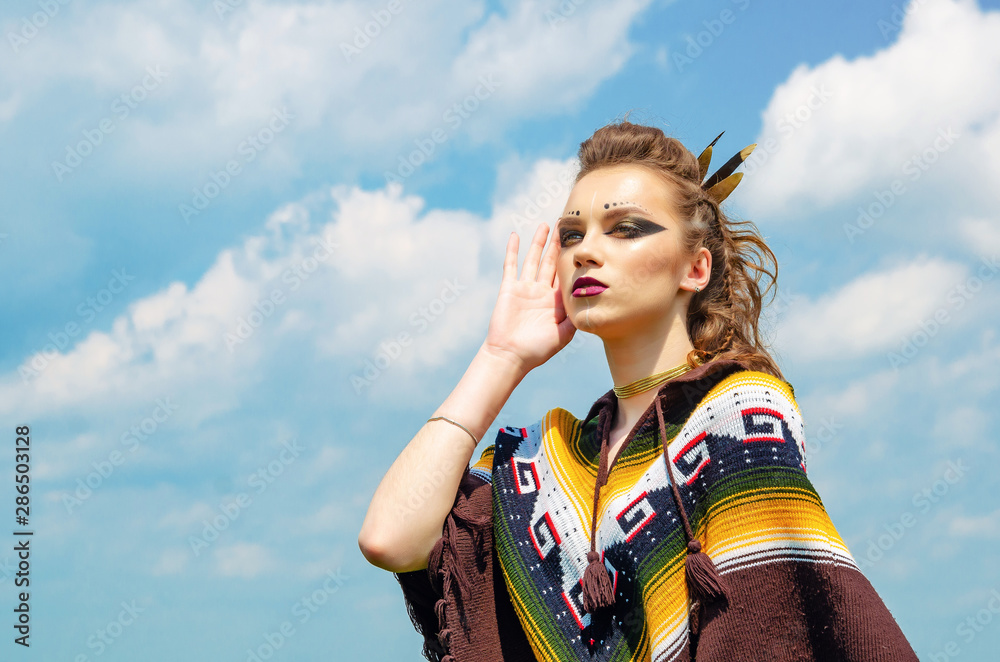 Portrait of a girl with makeup Amazon, Viking, aggressive war paint. Dressed in a poncho on the background sky. Portrait of a girl with makeup Amazon, Viking, aggressive war paint. Dressed in a poncho on the background sky.