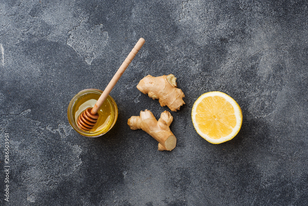 Lemon honey and ginger root on dark grey background with copy space. Ingredients for a tonic vitamin drink. Lemon honey and ginger root on dark grey background with copy space. Ingredients for a tonic vitamin drink.