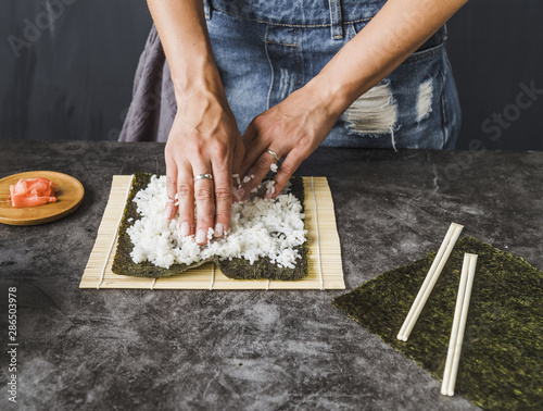 Hands arranging ingredients on sushi mat photo