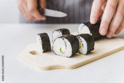 Person slicing sushi wrap on cutboard