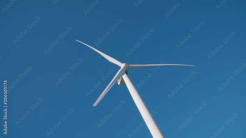 White wind energy tower mill against the blue sky. Green, clean, renewable energy White wind energy tower mill against the blue sky. Green, clean, renewable energy