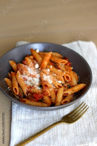 Plate of pasta with tomato sauce and eggplant  sprinkled with grated parmesan. Selective focus.