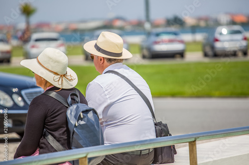 View of a senior couple sitting on a street bench, resting and enjoying the view