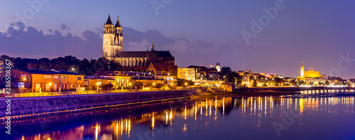 Magdeburg an der Elbe mit Magdeburger Dom, Johanniskirche, mit Promenade am Ufer des Flusses in Abendstimmung mit Abendrot und beleuchteten Gebäuden im Panorama