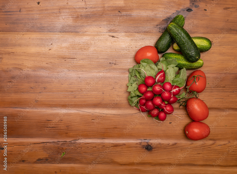 radishes tomato and cucumbers on wooden backround