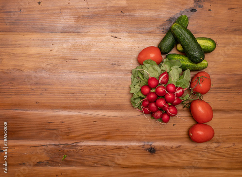 radishes tomato and cucumbers on wooden backround