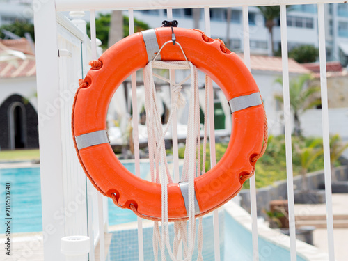 Closeyp orange lifebuoy on a white pool fence photo