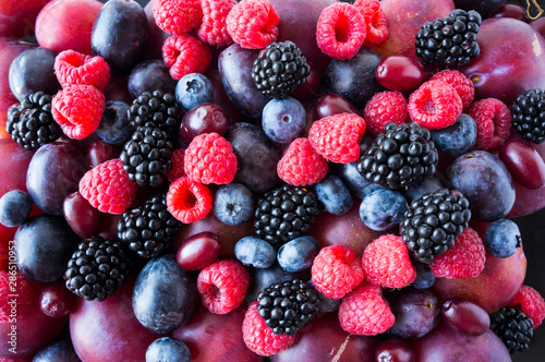 Ripe blackberries, blueberries, plums, pink grapes, raspberries. Mix berries and fruits. Top view. Background berries and fruits. Various fresh summer fruits. Black-blue and red food.
