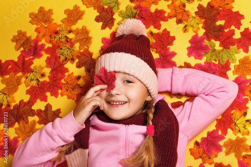 Top view of a happy child lying on the autumn leaves.