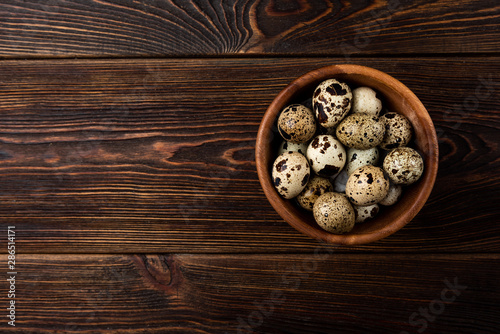 Quail eggs on dark wooden background.