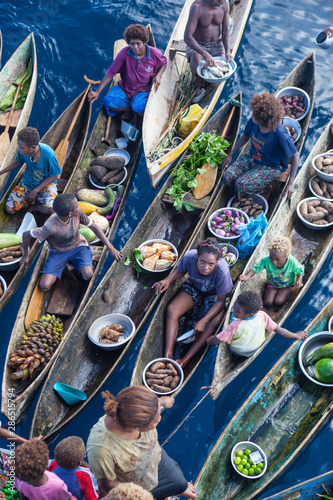 Fototapeta Naklejka Na Ścianę i Meble -  Villagers form a floating market, selling vegetables amid the Solomon Islands. This remote Melanesian region is part of the Coral Triangle due to its incredible marine biodiversity.