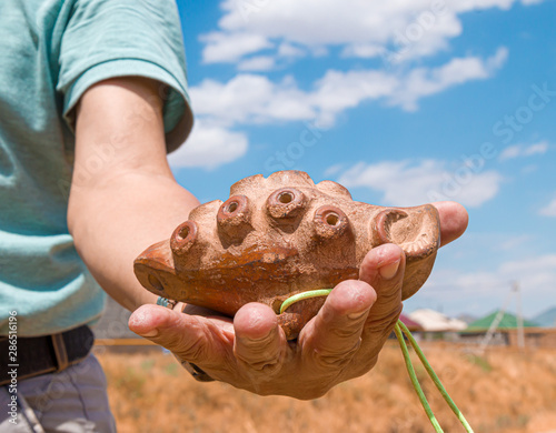 Ancient Asian musical instrument made of clay Otrar uldek in hand against the sky photo