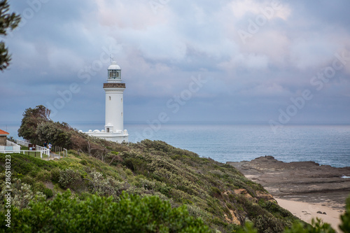 Lighthouse overlooking the sea with dark skies overhead.