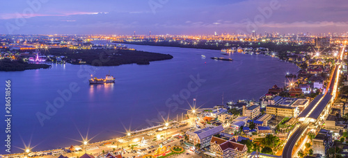 Panorama Street lights and street lighting from residential houses in the suburbs during sunset time, boat traffic on the Chao Phraya River, Samut Prakan, Thailand