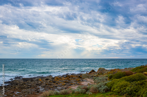 Cumulus clouds over the oceanfront view from rocky beach.