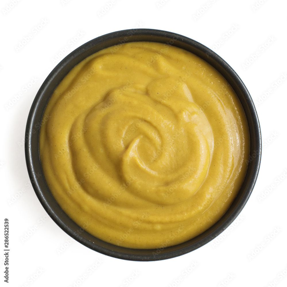 Mustard sauce in dark ceramic bowl isolated on white background. Top view