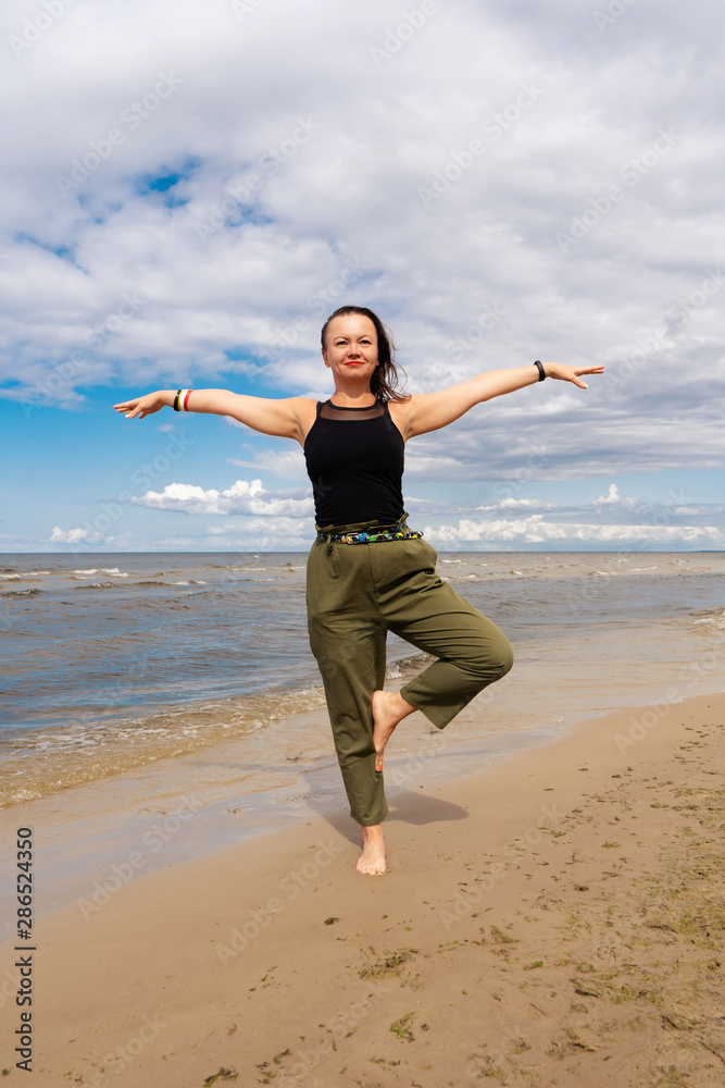 A woman practices yoga by the sea or ocean. Healthy lifestyle and health care. Outdoor sports. A woman practices yoga by the sea or ocean. Healthy lifestyle and health care. Outdoor sports.