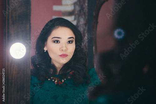 fashionable stylish portrait of Asian woman. the model looks in the mirror. girl in reflection. concept work, modeling