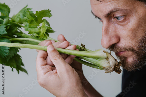 Culinary worker sniffing fresh stalks of green celery close-up