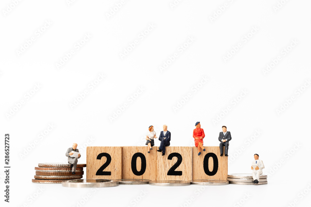 Miniature people : Business people sitting on wooden block number 2020