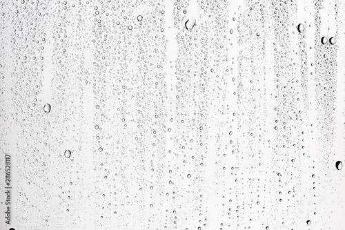 white isolated background water drops on the glass / wet window glass with splashes and drops of water and lime, texture autumn background photo