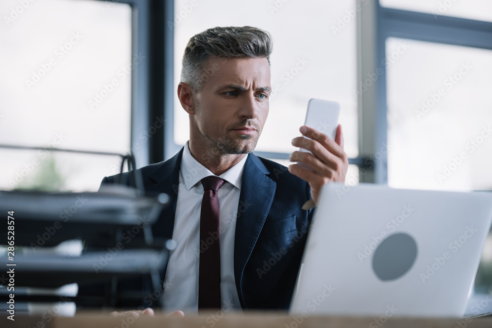 Fototapeta premium selective focus of businessman looking at smartphone in office