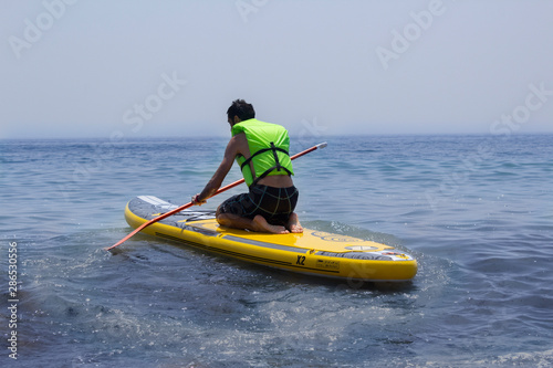 Man practicing paddle surf kneeling on the board