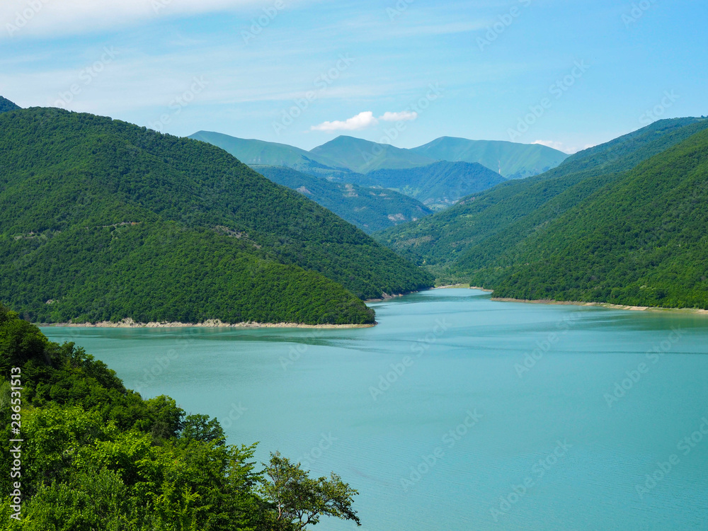 beautiful landscape overlooking a large blue lake in the mountains covered with forest.