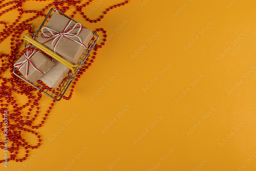 Gifts in a small shopping basket on a yellow background with Christmas decorations, concept, copy space. Gifts in a small shopping basket on a yellow background with Christmas decorations, concept, copy space.