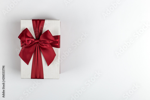Gift with a red ribbon and a bow on a white background, copy space.