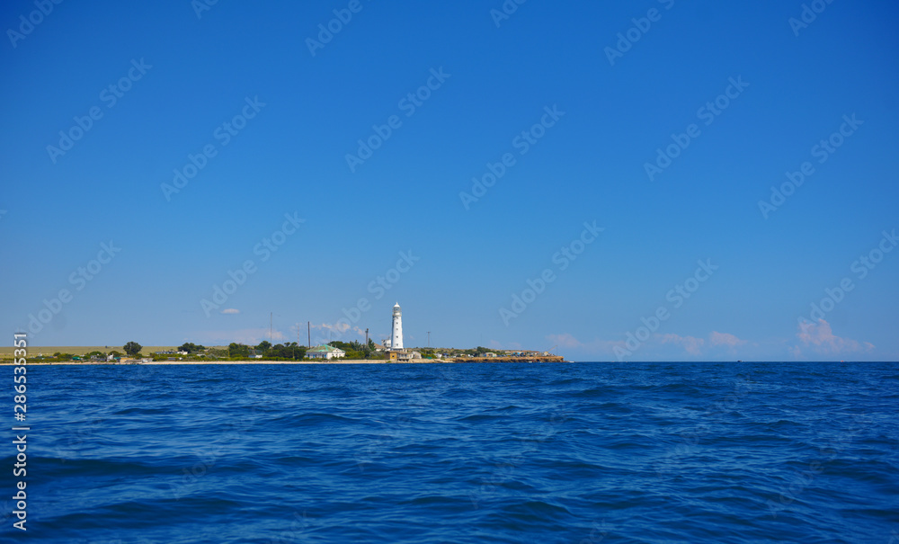 white lighthouse tower on the blue sea
