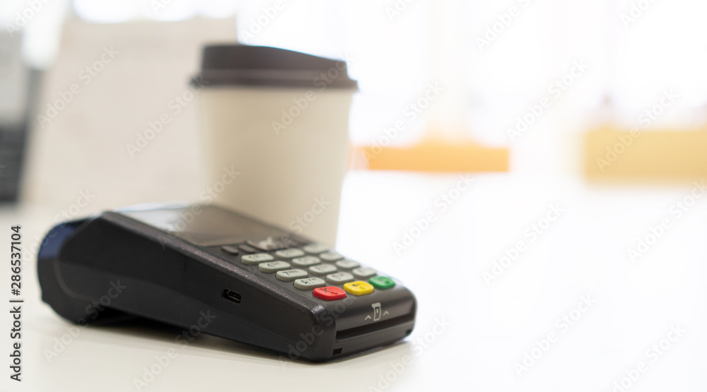 close credit card payment machine at table with white coffee cup on table in the cafe , contactless pay concept close credit card payment machine at table with white coffee cup on table in the cafe , contactless pay concept