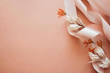 Feminine wedding desktop mockup with dry wildflowers and satin ribbon on coral background