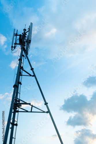 Silhouette of telecommunication tower of 4G and 5G cellular, mobile and internet station tower in cloudy sky background, vertical view.