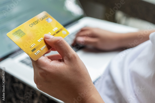close up woman hand holding credit card and using laptop, online shopping concept