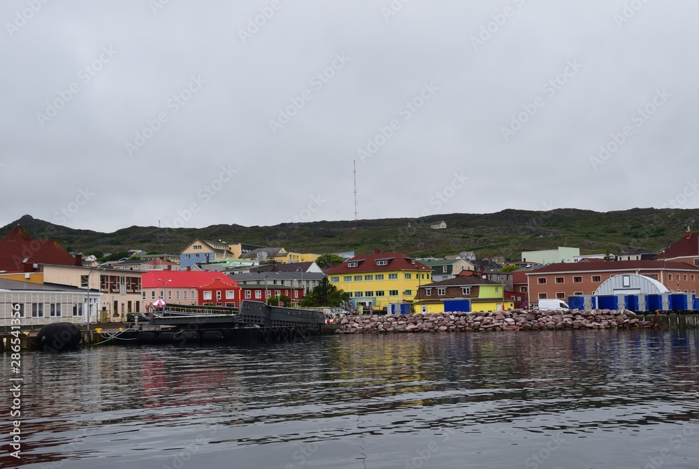 view from the ocean towards a large empty pier along the ocean front colorful buildings in the background, Saint Pierre, Saint Pierre and Miquelon