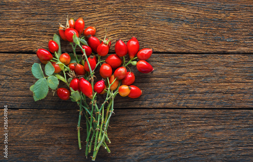 Canvas Print rosehip branches with red dog rose fruits on a brown wooden table