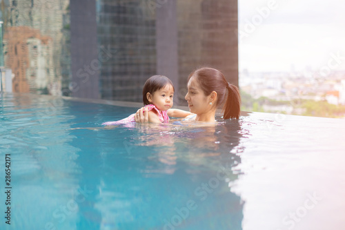 Mother and asian baby girl swimming in a pool. infants swimming. Baby swimming concept.